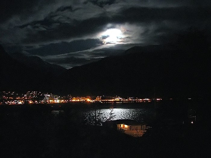 The Lights of Downtown Juneau with the Moon Shining on the Waters of Gastineau Channel.